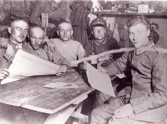 Here, a group of German soldiers relax in a dug-out, read the newspapers and 